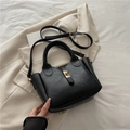 Elegante bolso de cubo en cuero sintético negro con cierre dorado y correa en un blazer - Negro