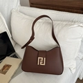 Brown leather baguette shoulder bag with gold geometric buckle on a white bed sheet - Brown