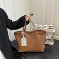 Close-up of brown tote bag featuring premium pebble grain texture and decorative tag - Brown