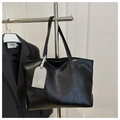 Dettaglio della texture della borsa tote in pelle nera morbida con etichetta grigia - Nero