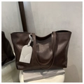 Detalle de bolso tote marrón chocolate en cuero texturizado con correas dobles finas - café