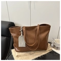 Detalle de bolso tote grande marrón texturizado con etiqueta de cuero patrón cocodrilo - Marrón