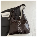 Detalle de bolso de hombro marrón brillante con remaches metálicos de estilo punk - café
