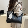 Large black tote bag in textured leather with a unique white arch-shaped charm - Black