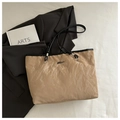 Close-up of beige tote bag with crinkled texture, black handles, and metallic logo detail - Khaki (Without Charm)