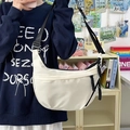 White minimalist nylon half-moon crossbody bag with adjustable black strap worn by model - Black