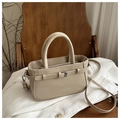 Detalle de bolso bandolera de cuero beige con hebilla decorativa sobre una silla - Caqui