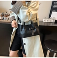 Detalle de bolso bandolera tejido negro con hebilla sobre una gabardina beige - Negro