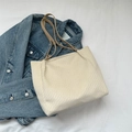 Chic beige quilted tote bag with brown straps displayed on a denim jacket background - Beige