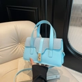 Lichtblauwe patchwork handtas met gouden gesp en schouderband op een leren stoel - Blauw