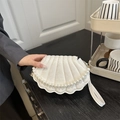 White seashell handbag with snake texture and elegant faux pearl handle on a wooden table - White