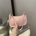 Pink snake skin textured hobo shoulder bag with elegant gold hardware on book prop - Pink
