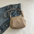 Minimalist khaki shell crossbody bag with adjustable fabric strap on blue denim background - Khaki