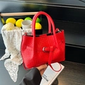 Rote Handtasche mit Webmuster, Gürtelschnalle und Umhängeriemen auf schwarzen Stufen - Rot