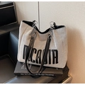 Dettaglio della borsa tote in tela intrecciata con catena in metallo e logo stampato - Nero