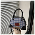 Detail der blau karierten Handtasche mit Cartoon-Apfelprint und schwarzem Lederbesatz - Schwarz