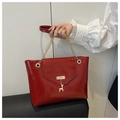 Detail der glänzenden roten Ledertasche mit goldenem Elchanhänger und Kettenelementen - Rot