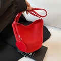 Red suede bucket bag with woven handle and circular charm in a stylish casual design - Red