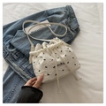 Dettaglio borsa a secchiello bianca con manico di perle e fiocchi neri su denim - Fiocco Bianco