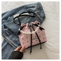 Dettaglio borsa a secchiello rosa con motivi a fiocco nero e manico di perle eleganti - Fiocco Rosa