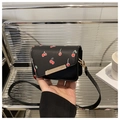 Close-up of a small black cherry print crossbody bag with a gold metal clasp and thin strap - Cherry Black
