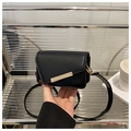 Detail of a black matte leather crossbody bag featuring a unique gold metal bar lock - Black
