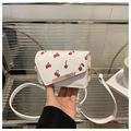 Detail of white PU leather crossbody bag with red cherry patterns and gold metal bar - Cherry White