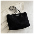 Close-up of black corduroy tote bag with FANYISSA BAGS logo on a white jacket - Black