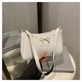 Dettaglio borsa baguette bianca lucida con fiocco dorato su sfondo minimalista pulito - Bianco