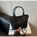 Detail of black woven straw tote bag featuring fashion leather label and knotted handles - Black