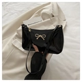 Detail of glossy black patent leather shoulder bag with gold metal bow and floral zipper - Black