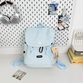 Detail of light blue outdoor backpack with plush charm and fashion label on front pocket - Large Blue With Brown Cloud Tag No Charm