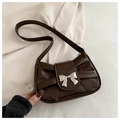 Detailed view of dark brown shoulder bag with metallic silver bow buckle on beige blazer - Brown