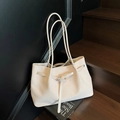 Elegante weiße gewebte Leder-Shopper-Tasche mit langen Schultergurten auf Holzsockel - Beige