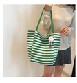 Detail of green striped canvas tote bag with white pompom charm and metal brand tag - With Plush Charm / Green