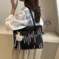 Black embroidered tote bag with bear charm shown on model in a cozy indoor setting - Black (With Pendant)
