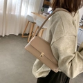 Minimalist beige baguette bag with gold buckle in an aesthetic indoor setting - Khaki