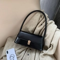 Elegante schwarze Leder-Baguette-Tasche mit goldener Schnalle auf beigem Strickpullover - Schwarz