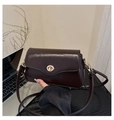 Detail einer dunkelbraunen Lackleder-Baguette-Tasche mit goldenem runden Verschluss - Schwarz