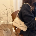 Minimalist cream faux leather baguette bag with gold twist lock worn by a model - Khaki