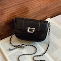 Schwarze Stepptasche mit silberner Kette und Metallverschluss auf einem Vintage-Buch - Schwarz