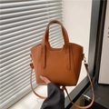 Bolso bombonera marrón minimalista de piel granulada lychee bajo luz natural suave - Marrón