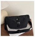 Close-up of black nylon crescent bag with metal 'M' logo on a wooden desk setting - Black