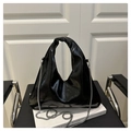 Detail of black glossy triangular handbag with elegant knotted handle and silver chain - Black