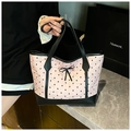 Dettaglio della borsa tote rosa con cuori neri, bordi in pelle e fiocco decorativo - Cuore