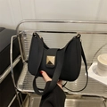Detail of minimalist black shoulder bag with gold square buckle on a stylish chair - Black