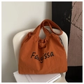 Detail of the orange nylon tote bag showing the letter print and drawstring closure - Orange
