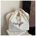 Detail der weißen großen Canvas-Tasche mit Fanyissa-Aufdruck auf minimalistischem Stuhl - Weiß