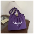 Detailansicht der lila Nylon-Tasche mit Kordelzug und Fanyissa-Logo auf Holztisch - Lila