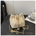 Detailed view of woven bucket bag featuring drawstring closure and pearl accents - Off White